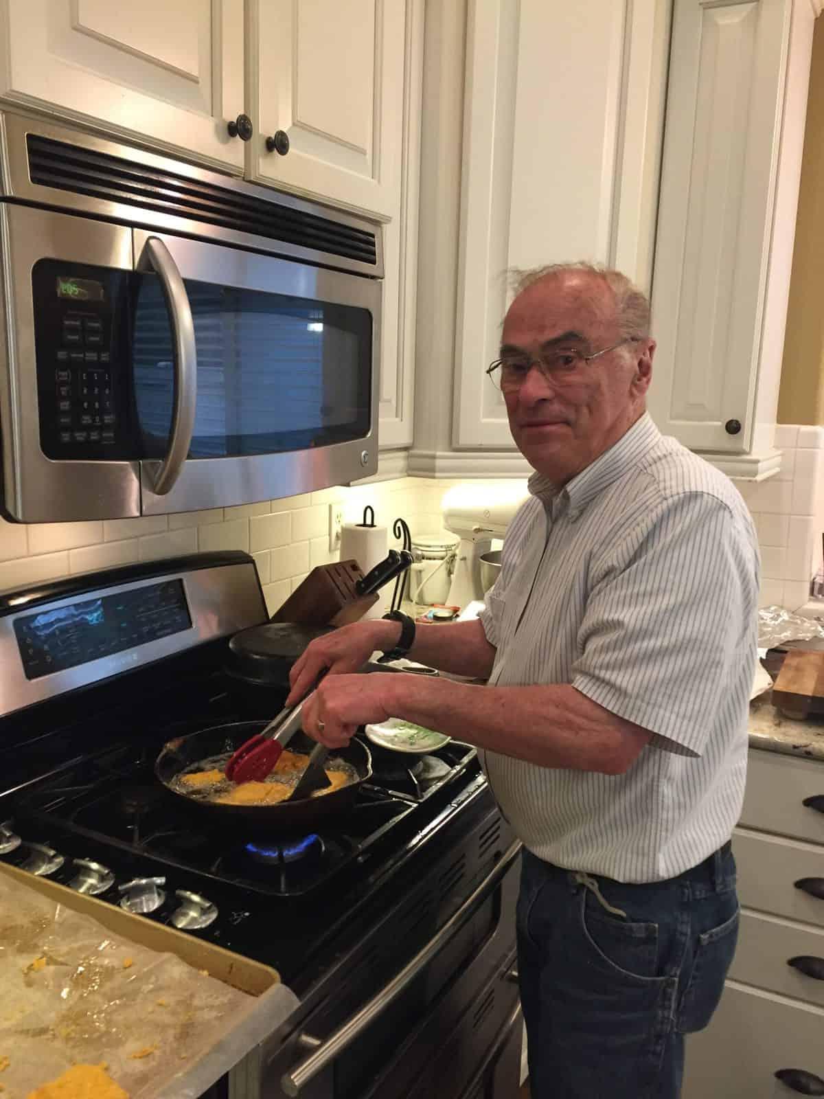 Melinda's dad frying cod in a cast iron skillet on the stove.