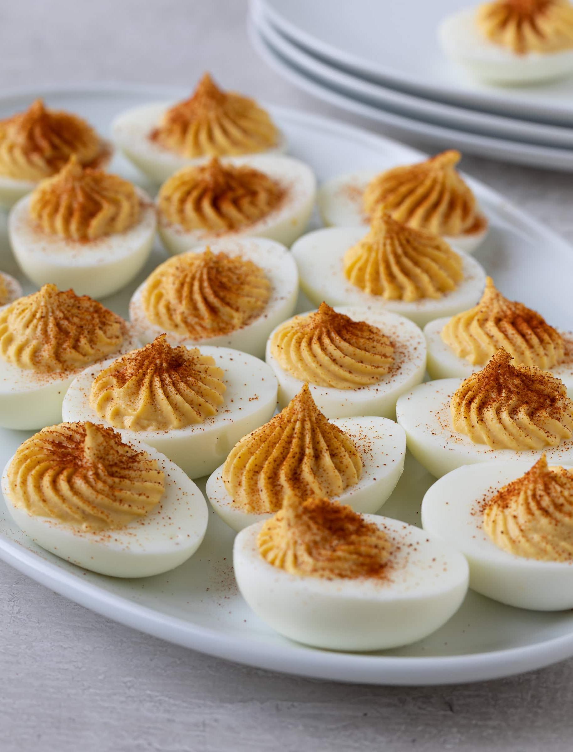A platter of finished deviled eggs topped with red paprika as garnish.