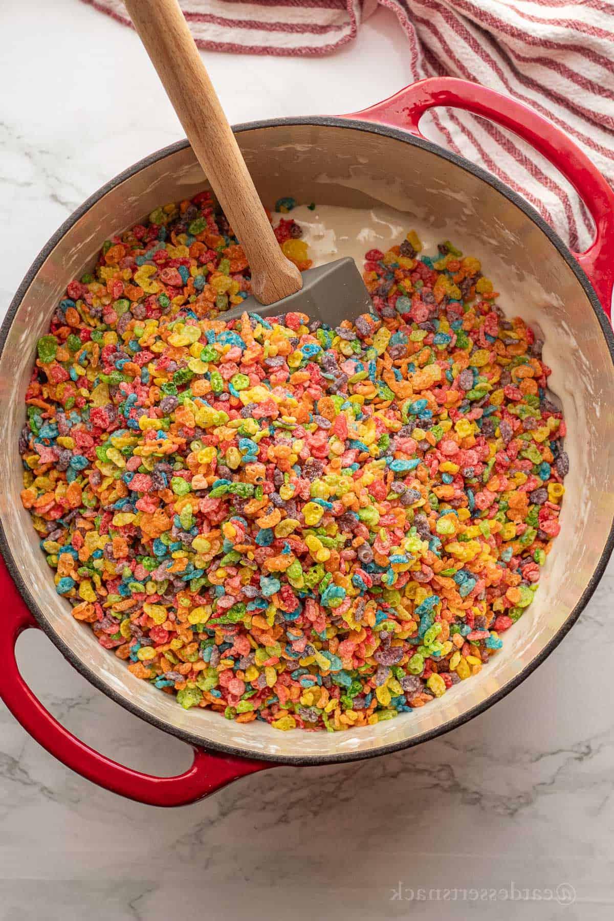 Fruity pebbles in marshmallow mixture in red pot.