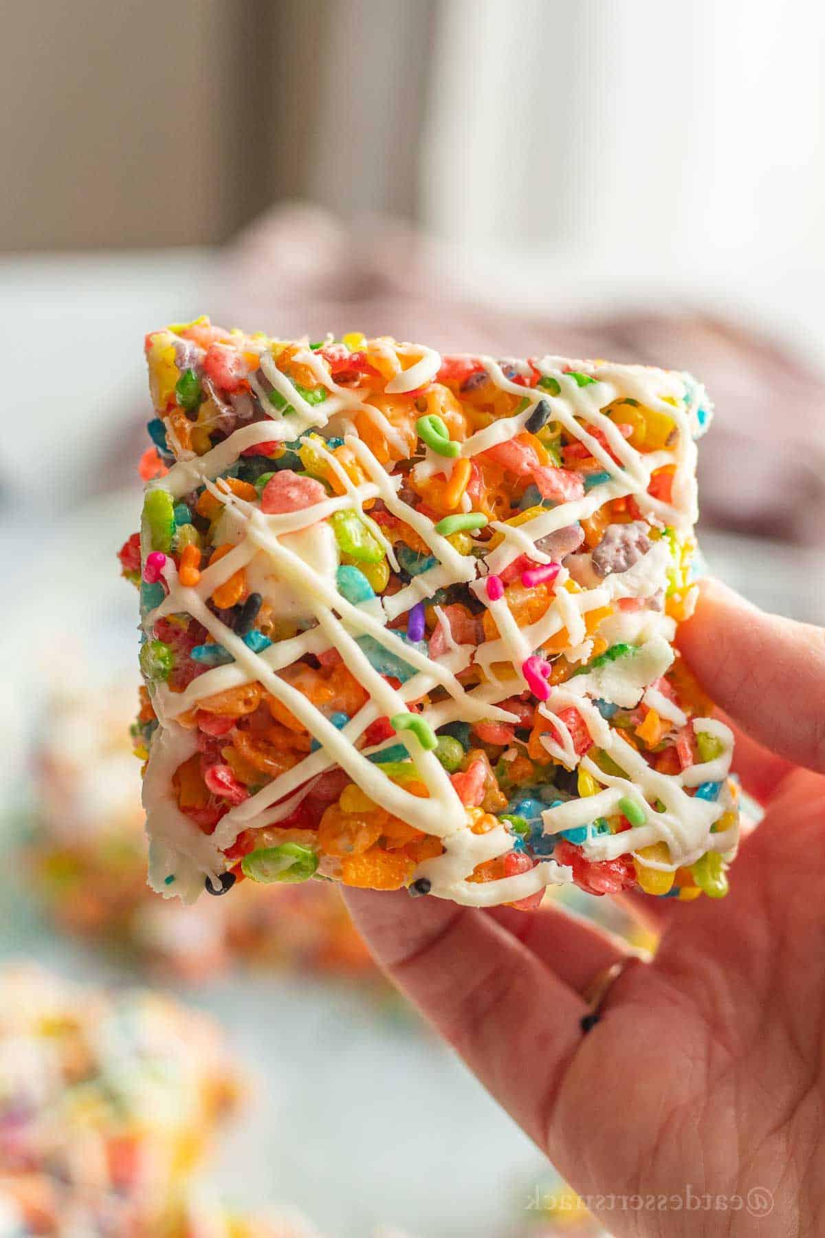 Slice of fruity pebble crispy treats with white chocolate drizzle on top.