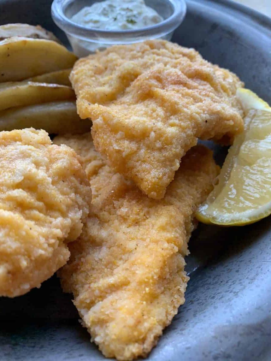 Three pieces of fried cod on a metal plate.