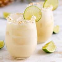 Side view of two glasses of tropical margaritas with limes.