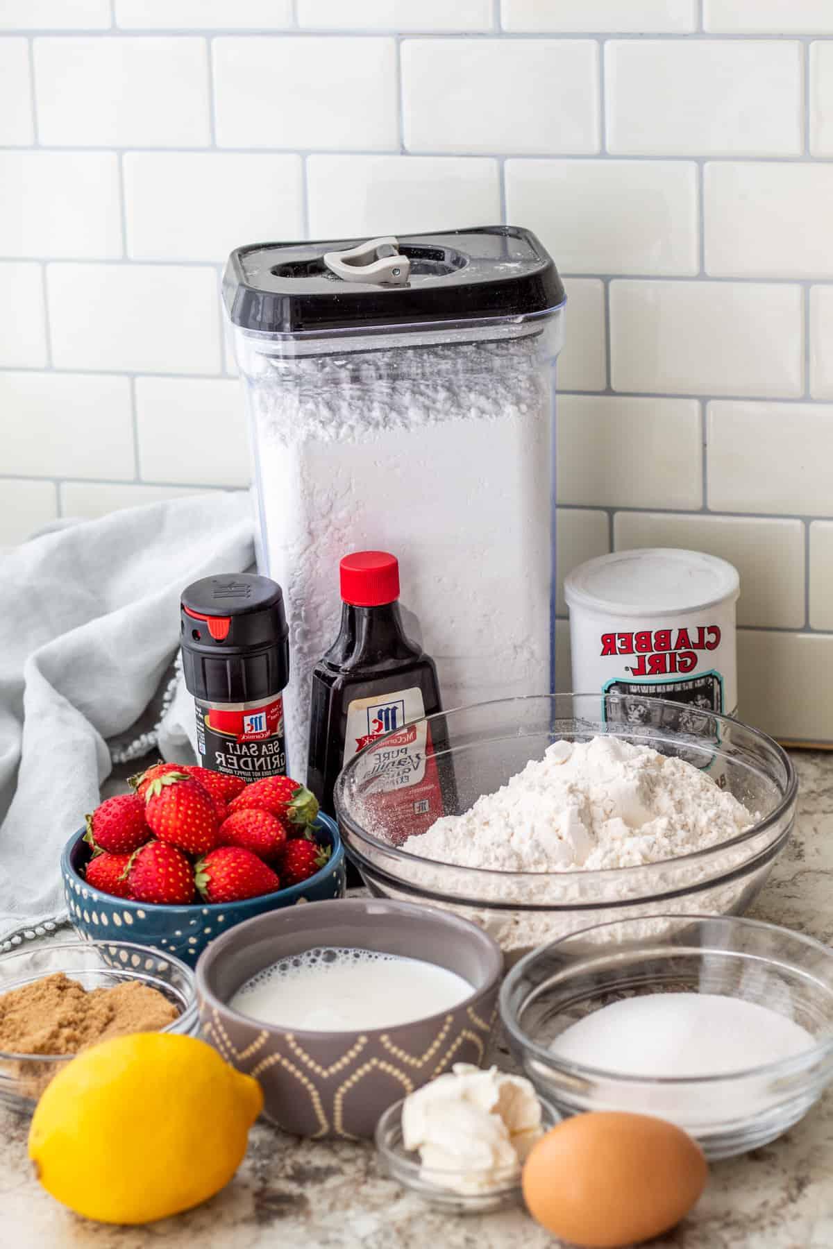 Strawberry loaf cake ingredients laid out on white counter top.